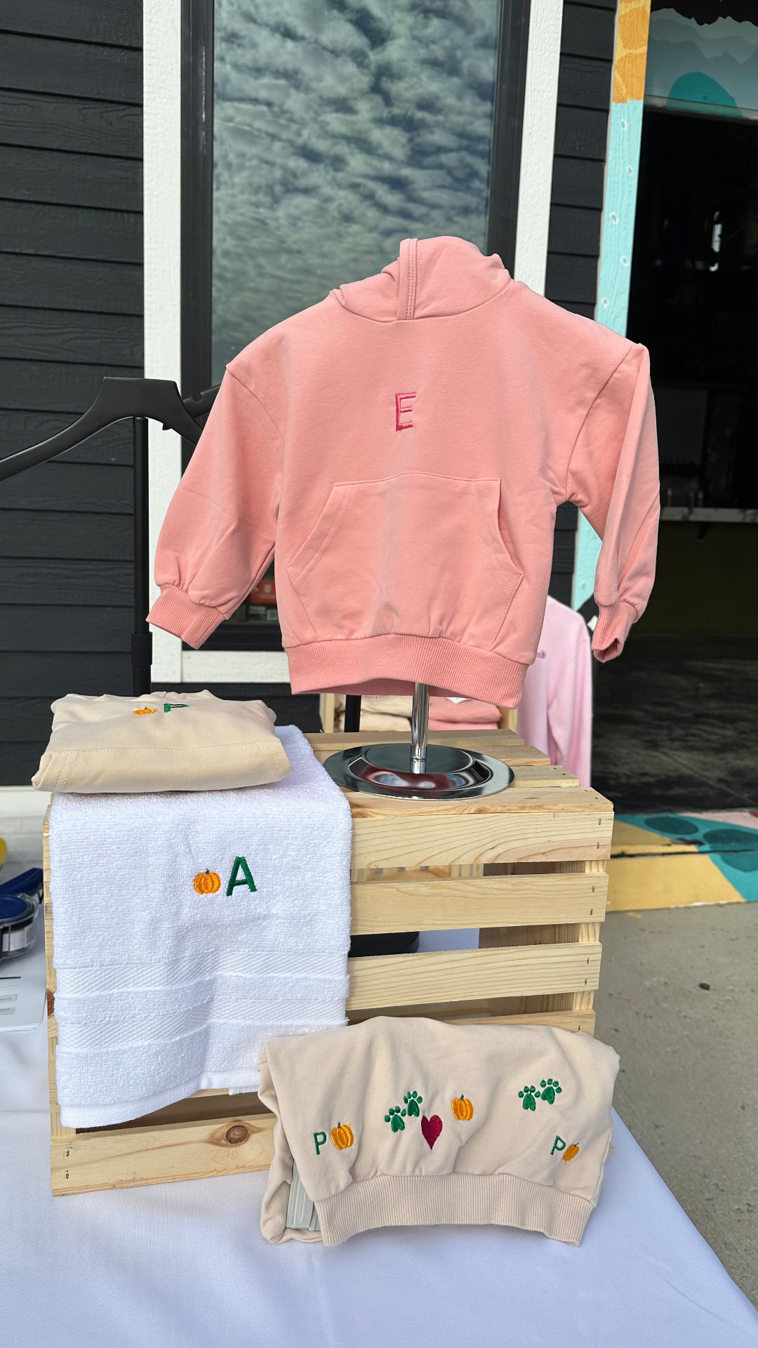 Embroidered hoodies and hand towels with initials and icons displayed at a live stitching event