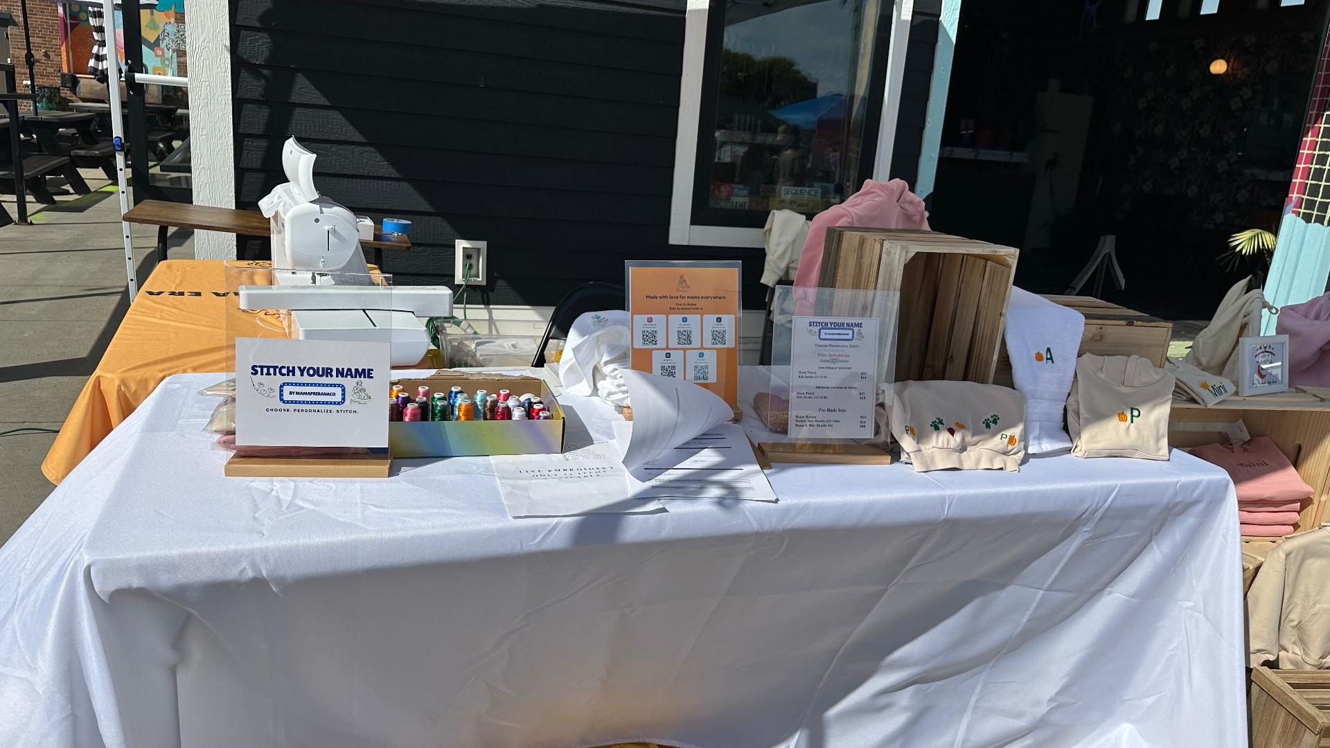 MamaPreranaCo live embroidery booth at a Fargo market with a single-needle machine stitching custom keepsakes